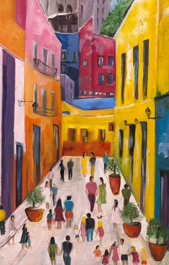 People strolling through a narrow street framed by vivid yellow, pink, orange and blue buildings, balconies and potted plants.